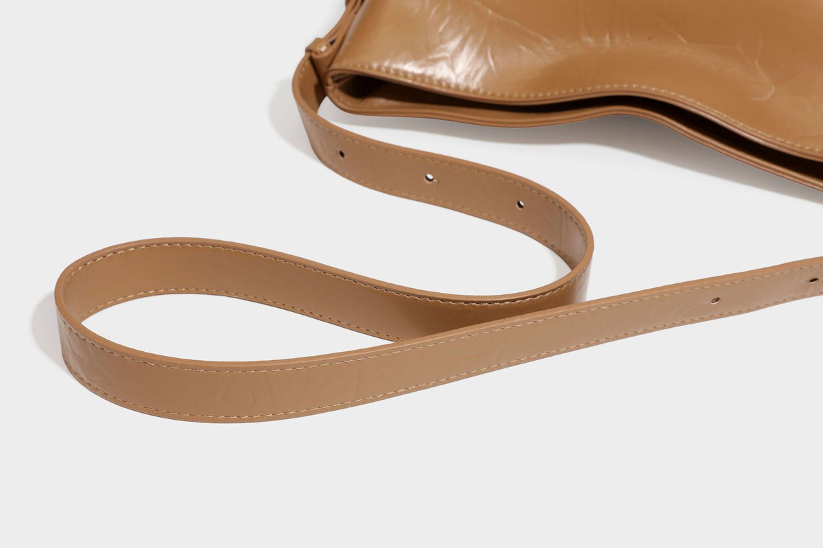 Lässig fallende Hobo-Schultertasche mit offenem Oberteil aus glänzender, karamellbrauner Lederoptik, mit Logo-Beschlägen in Goldoptik und langem, verstellbarem