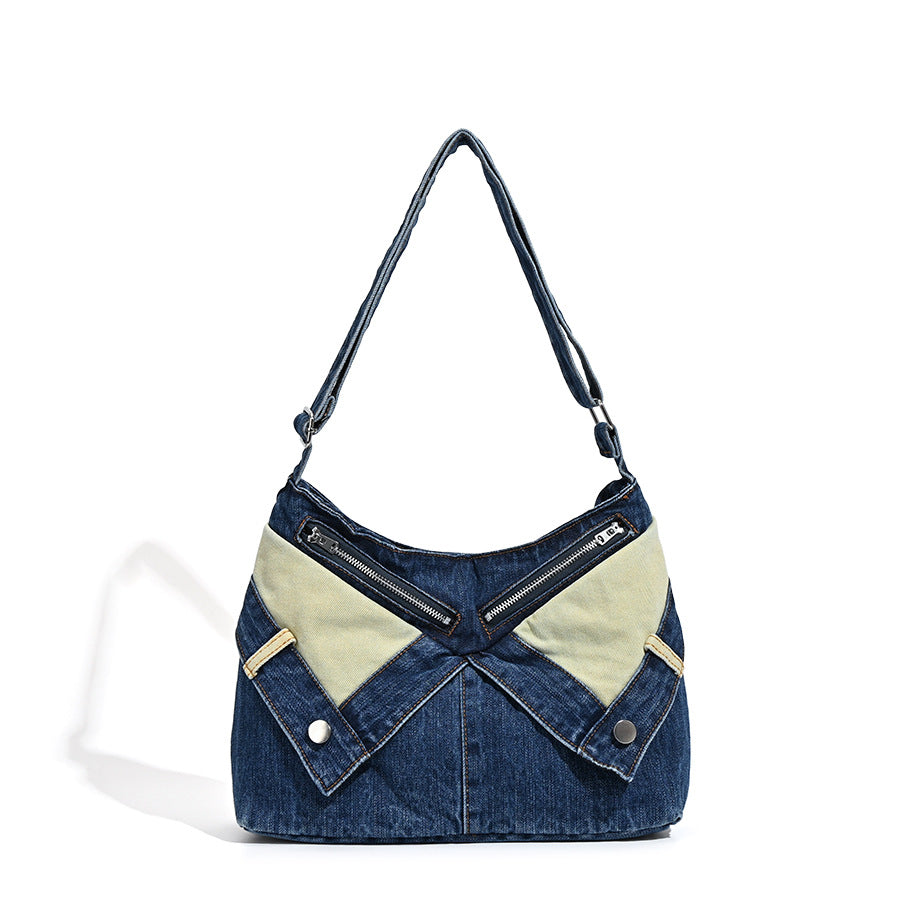 Schultertasche aus indigoblauem Denim mit hellen Kontrastpartien, sichtbarem Reißverschluss in Silberoptik, Druckknopfdetails und langem verstellbarem