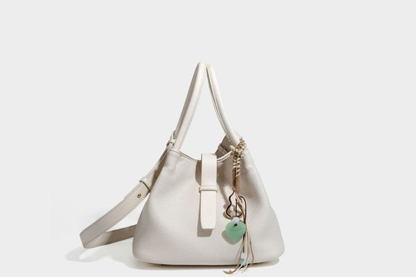 Pebbled leather-look bucket tote bag with rolled double handles, drawstring closure, braided cord charm, and detachable