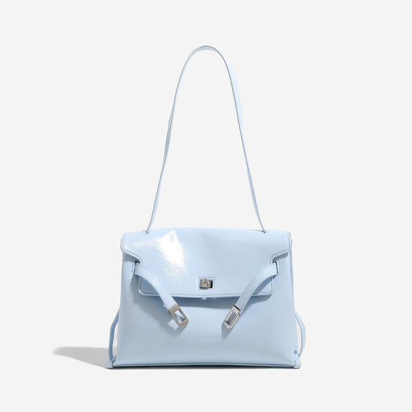Structured trapezoidal flap satchel bag with silver-tone turn-lock clasp, decorative front strap tabs, gusseted sides, and
