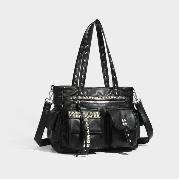 Black leather-look tote bag with silver pyramid studs on handles and front panel, multiple flap and zip exterior pockets