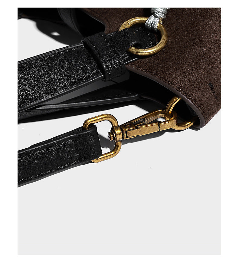 Small structured trapezoid tote bag in matte suede-look finish with black contrast trim, gold-tone front clasp, tassel charm