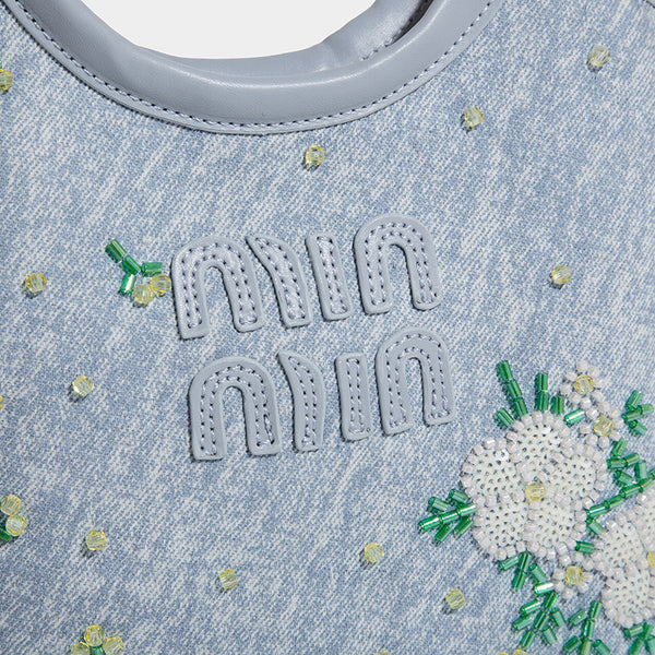 Kleine hellblaue Mini-Tote-Bag aus Stoff mit weißer Blumenverzierung aus Perlen, runden Tragegriffen, silberfarbenen Metallelementen und