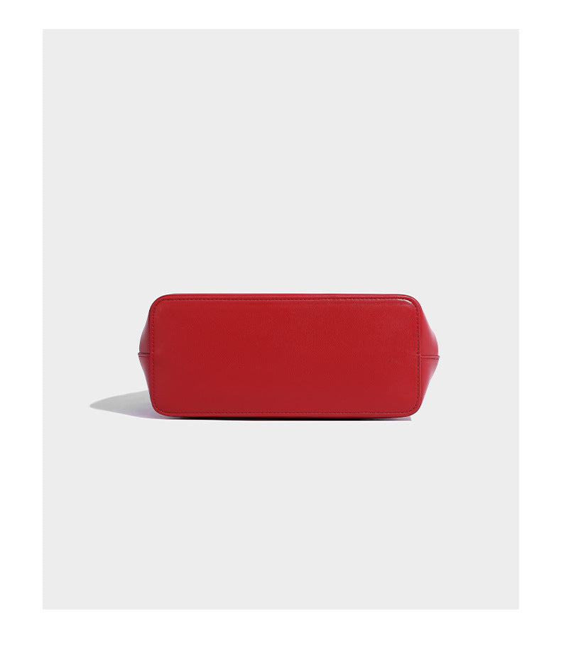 Small structured shell top-handle bag in red with heart charm and braided cord detail, smooth leather-look finish, detail