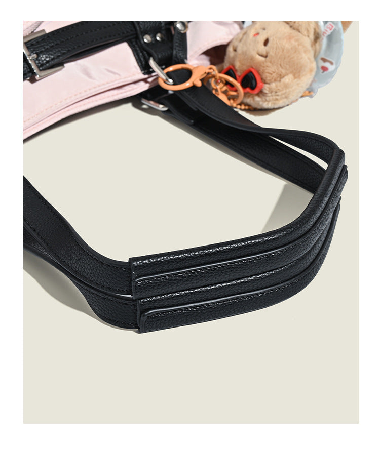 Pale pink nylon tote bag with black leather-look trim, double top handles, side zip pocket, and detachable crossbody strap