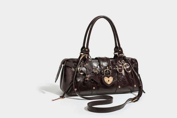 Glossy dark brown structured Boston satchel with heart-shaped lock charm, star pendant, rivet studs, multi-strap front panel