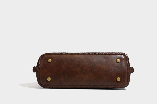 Structured woven-embossed leather-look satchel with dual rolled top handles, gold-tone turn-lock closure, and detachable
