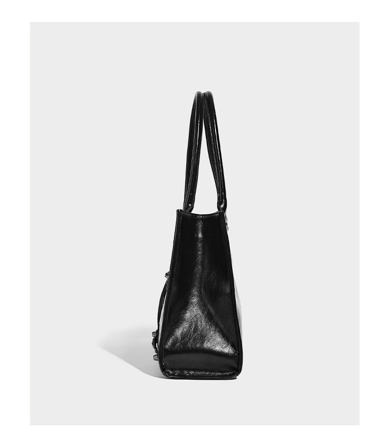 Large structured leather-look tote bag with front zip pocket, moto hardware accents, and long double shoulder straps, detail