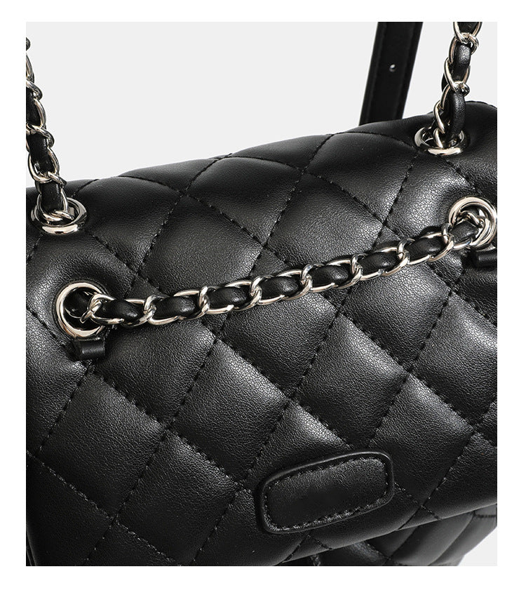 Black diamond-quilted backpack handbag with silver-tone chain flap accent and adjustable shoulder straps, detail view 21