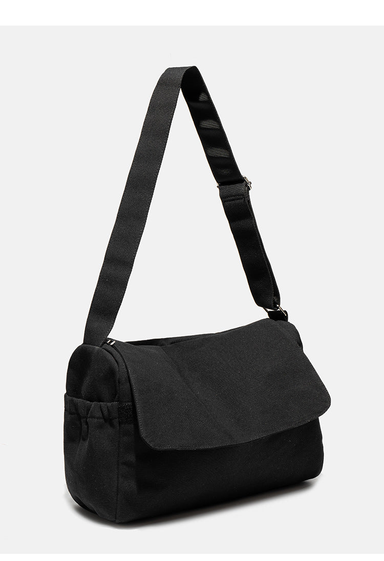 Große schwarze Messenger-Tasche aus mattem Canvas mit Überschlag vorn, Reißverschluss oben, elastischen Seitentaschen und verstellbarem silberfarbenem