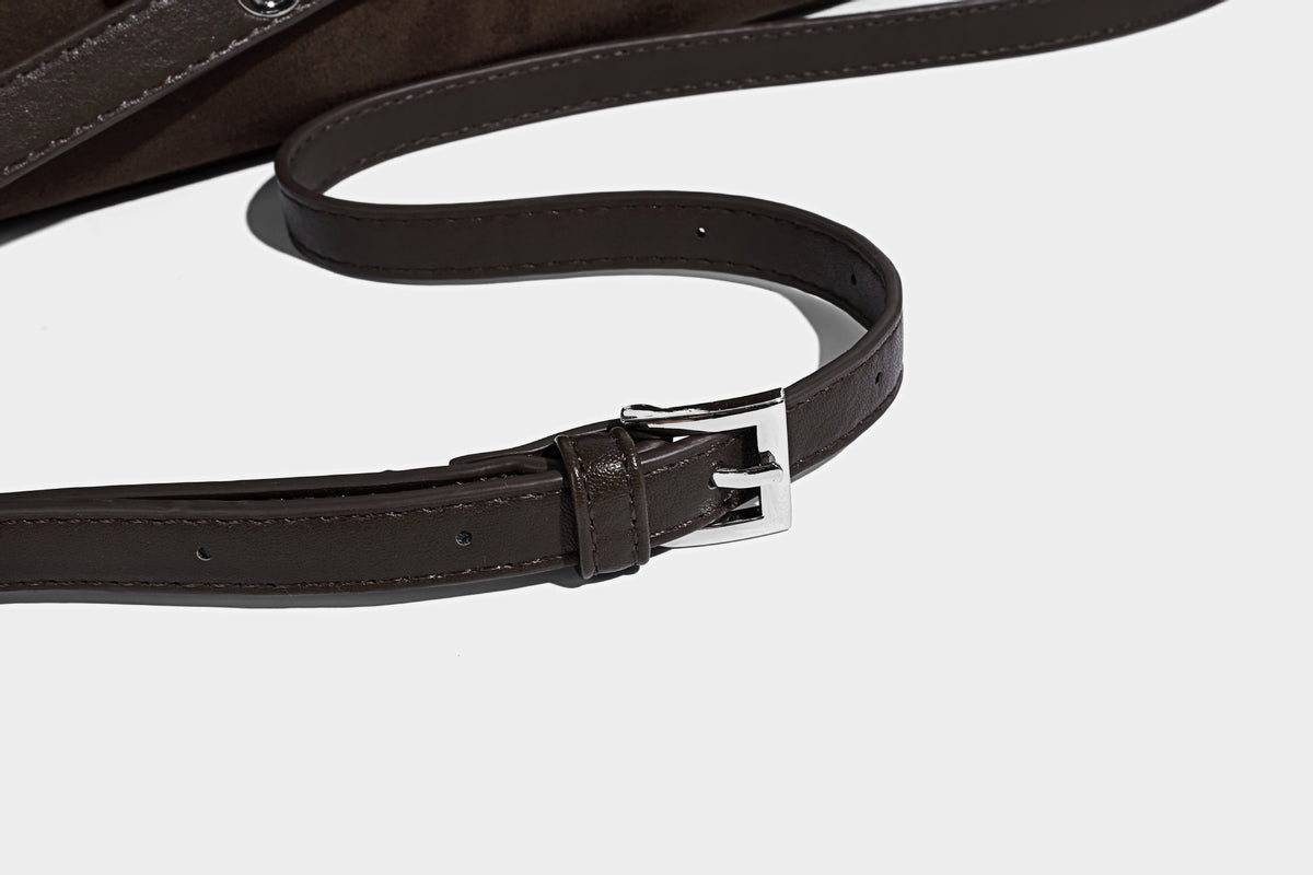 Hobo-Schultertasche in Dunkelbraun mit velourslederartiger Oberfläche, silberfarbener Gürtelschnalle und Ösenbeschlägen, verstellbarem Riemen, Detailansicht