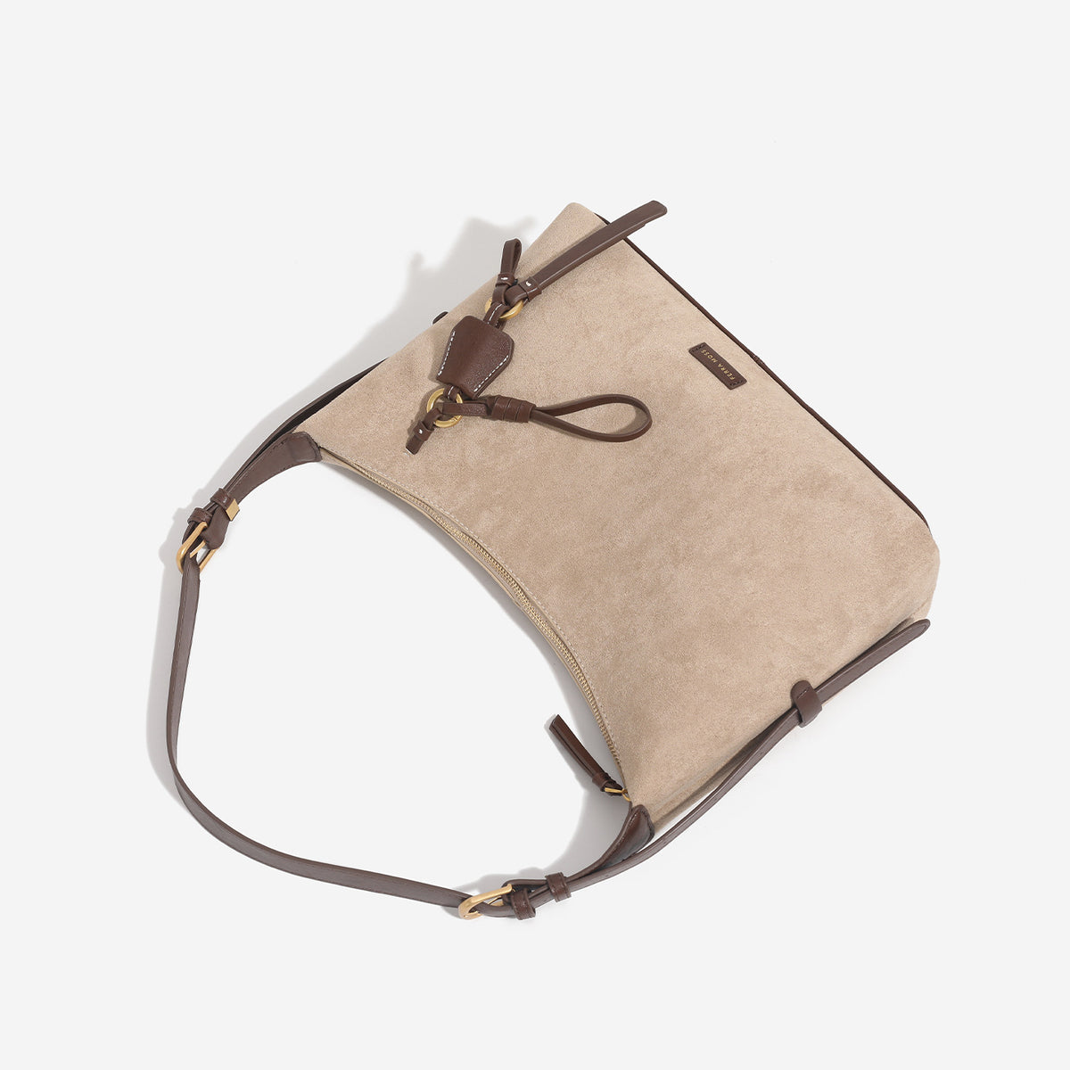 Sand beige slouchy hobo shoulder bag with dark brown trim, adjustable strap, gold-tone hardware, and decorative charm