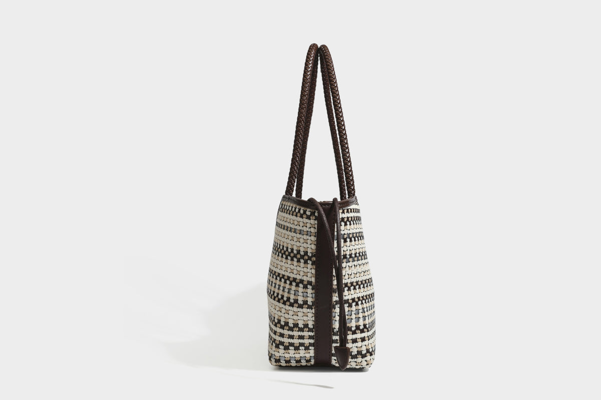 Large woven checker-pattern tote bag with dark braided shoulder straps, leather-look trim, and drawstring side ties, detail