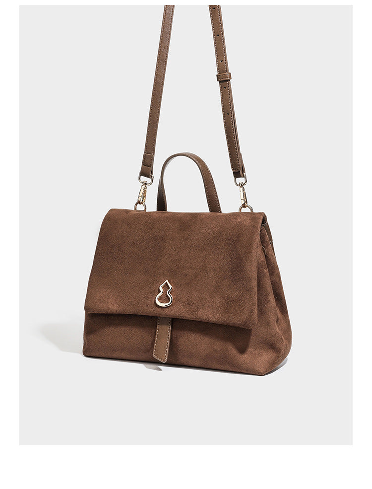 Formstabile Satchel-Tasche mit Überschlag in matter Veloursleder-Optik, goldfarbenen Emblem-Details, kurzem Tragegriff und verstellbarem Crossbody-Riemen