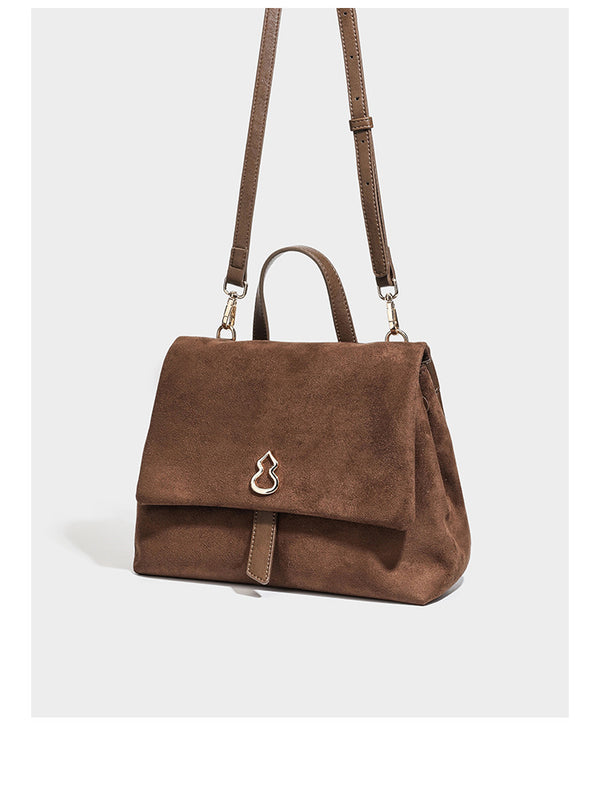 Formstabile Satchel-Tasche mit Überschlag in matter Veloursleder-Optik, goldfarbenen Emblem-Details, kurzem Tragegriff und verstellbarem Crossbody-Riemen