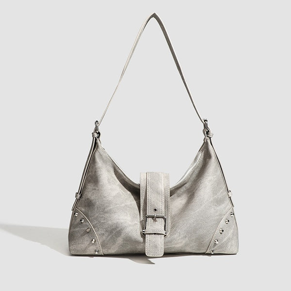 Slouchy trapezoid hobo shoulder bag with distressed textured finish, silver rivet corner accents, centre buckle strap, and