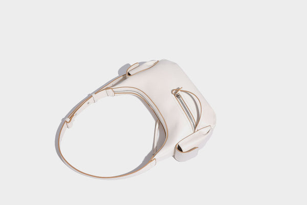 Smooth leather-look crescent shoulder bag with front zip pocket, side flap pockets, adjustable strap, and silver-tone, detail