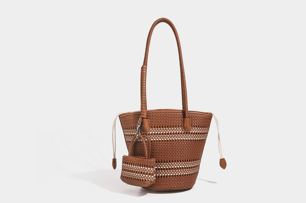 Light blue open-weave woven bucket tote bag with long braided shoulder straps, drawstring side ties, and attached mini pouch
