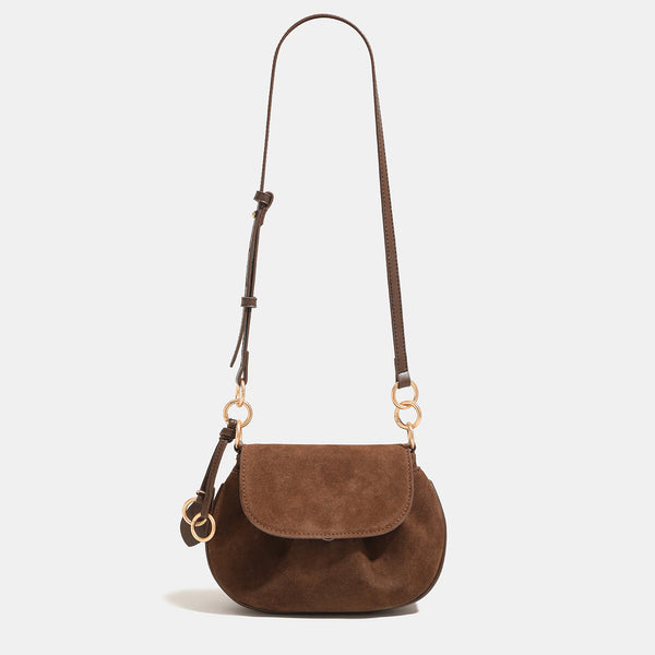Small rounded flap crossbody saddle bag with gold-tone ring hardware and adjustable strap, front view