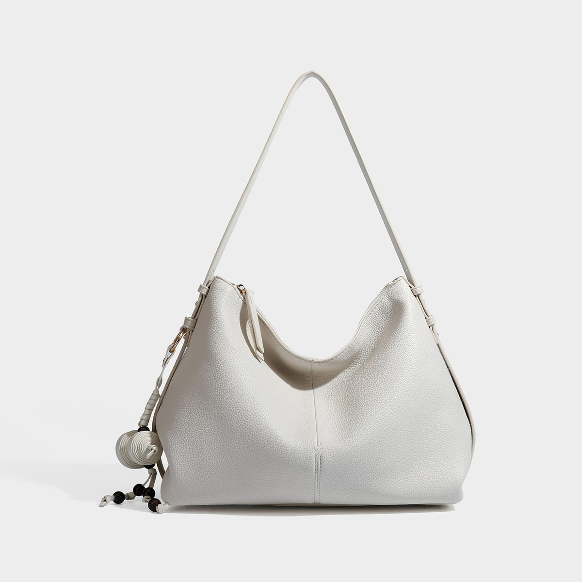 Slouchy hobo shoulder bag with pebbled leather-look finish, zip-top closure, gold-tone hardware, and hanging bead charm