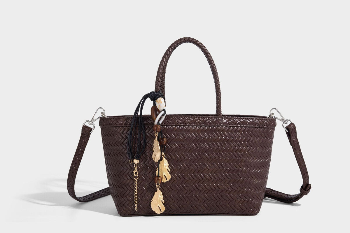 Structured chevron woven leather-look tote bag with braided top handles, gold feather charm, and adjustable shoulder strap