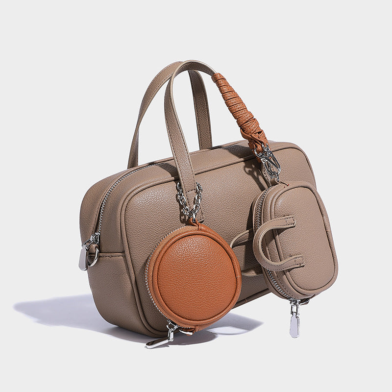 Structured pebbled leather-look Boston bowling bag in tan with blue detachable round mini pouch, dual top handles, and
