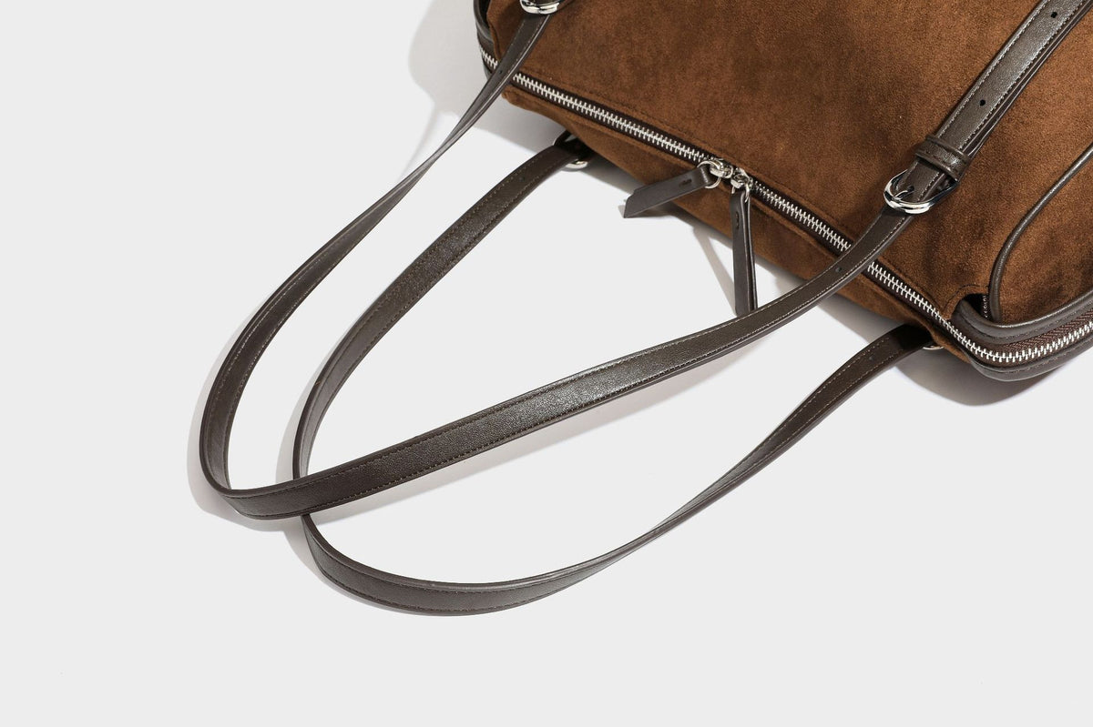 Large brown suede-finish barrel shoulder bag with dark leather-look trim, silver-tone zippers, dual top handles, and long