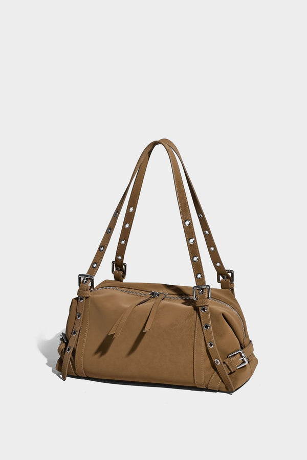 Weiche, zylinderförmige Schultertasche in Dunkelbraun mit silberfarbenen Riemen mit Ösen, Reißverschluss oben, seitlichen Schnallenbeschlägen und Quaste