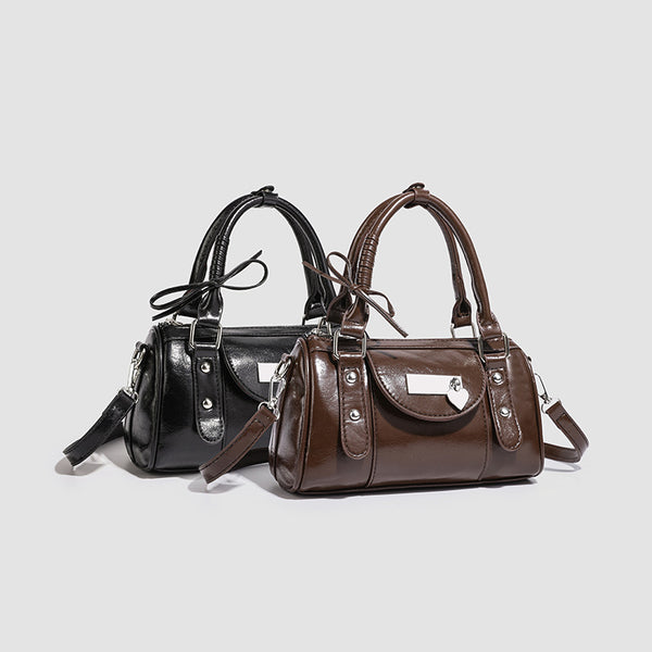 Kleine strukturierte Henkeltasche in glänzender Lederoptik mit Henkeln mit Schleifendetails und Vordertasche mit Herzverschluss, Detailansicht