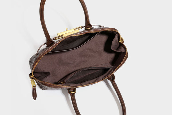 Structured woven-embossed leather-look satchel with dual rolled top handles, gold-tone turn-lock closure, and detachable