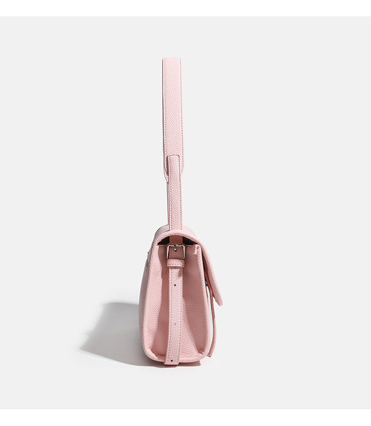 Compact structured flap satchel bag with pebbled texture, snap closure, front strap tabs, and long adjustable crossbody