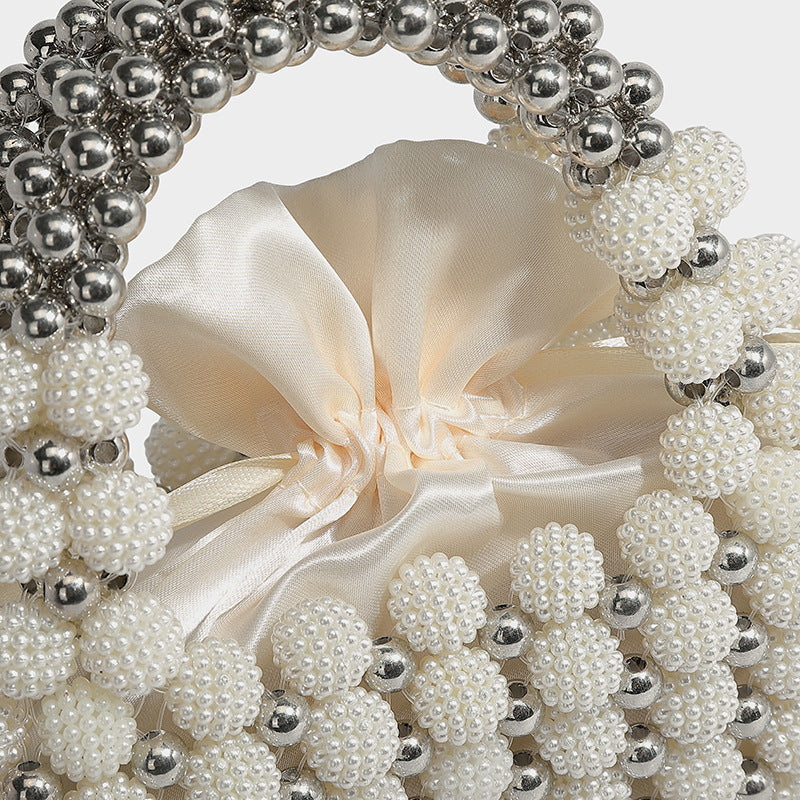 Small boxy pearl-bead mini top-handle bag with silver metallic bead accents, satin floral detail, and long beaded shoulder