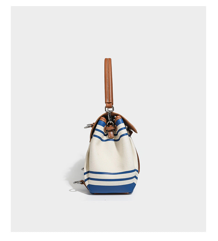 Cream canvas bucket bag with blue horizontal stripes, tan leather-look flap and trim, drawstring closure, silver-tone, detail