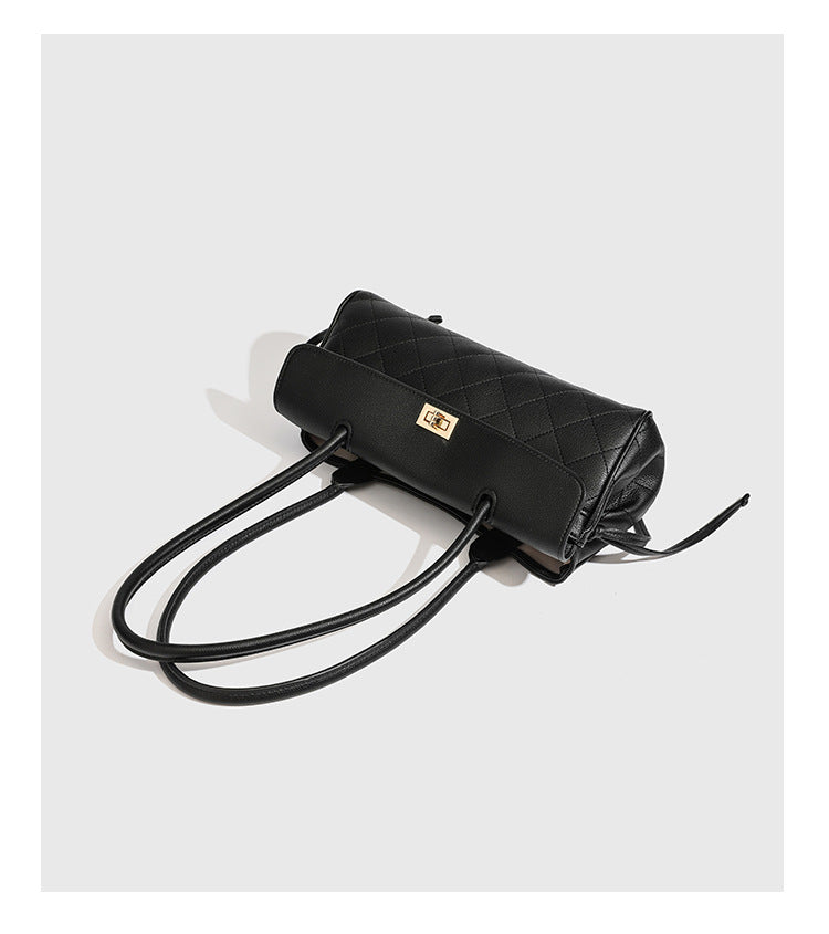 Structured black diamond-quilted shoulder bag with gold-tone turn-lock flap closure and dual round shoulder straps, detail