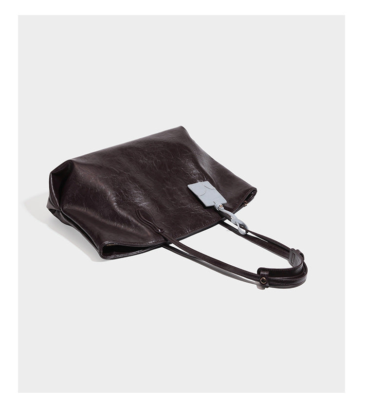 Übergroße, weich fallende Tote-Bag in dunklem Bordeauxrot mit glänzender, geknautschter Lederoptik, zwei langen Schulterriemen und Kontrast