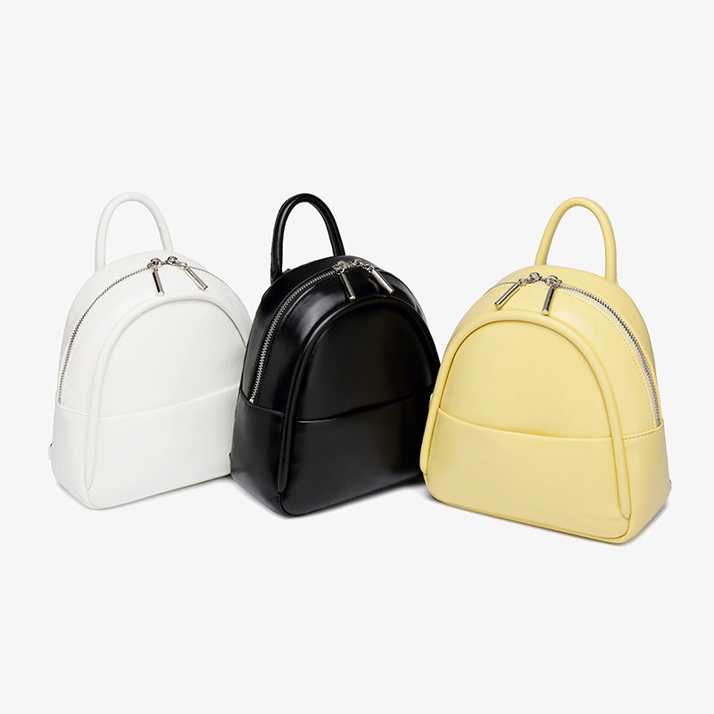 Kleine kuppelförmige Mini-Rucksackhandtasche in Pastellgelb mit glatter Oberfläche in Lederoptik, bogenförmigem Reißverschluss oben und silberfarbenen Details