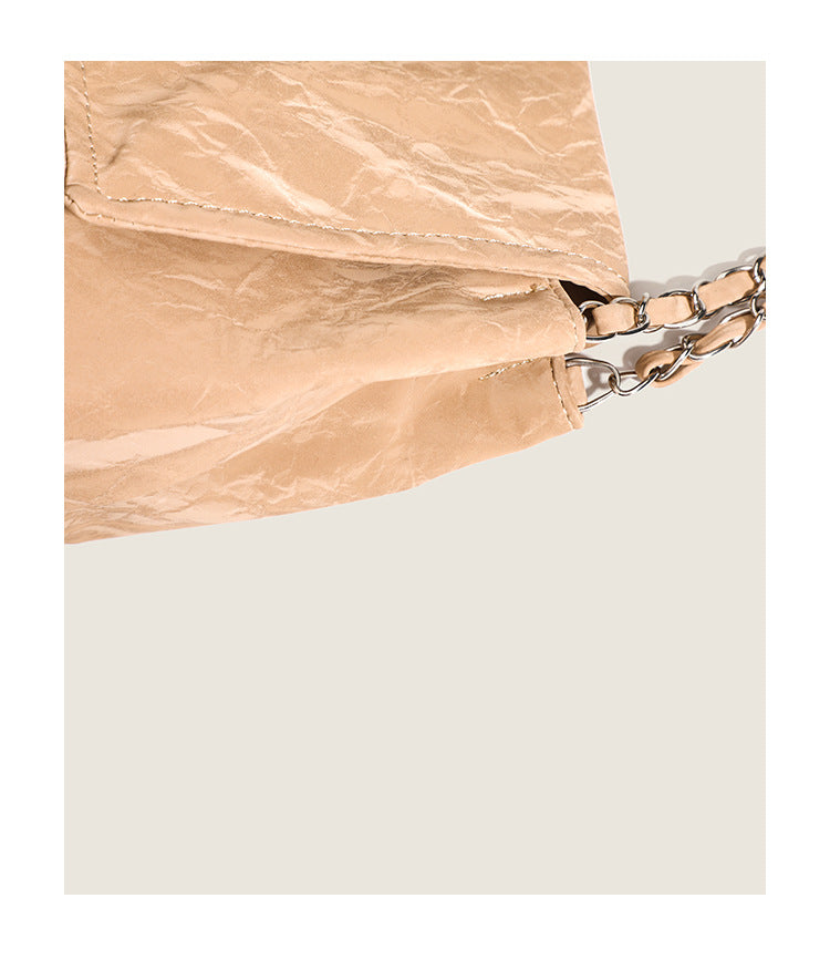 Crinkle-finish leather-look shoulder bag with woven tan-and-metal chain strap and front flap turn-lock closure, detail view