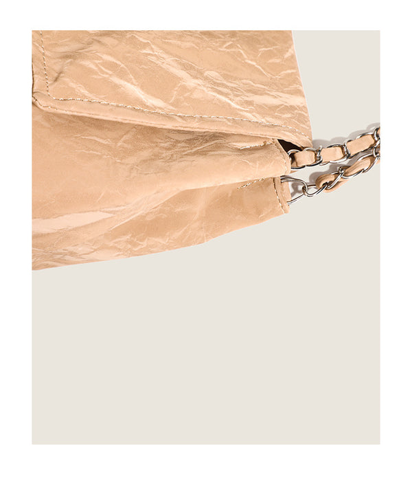 Crinkle-finish leather-look shoulder bag with woven tan-and-metal chain strap and front flap turn-lock closure, detail view