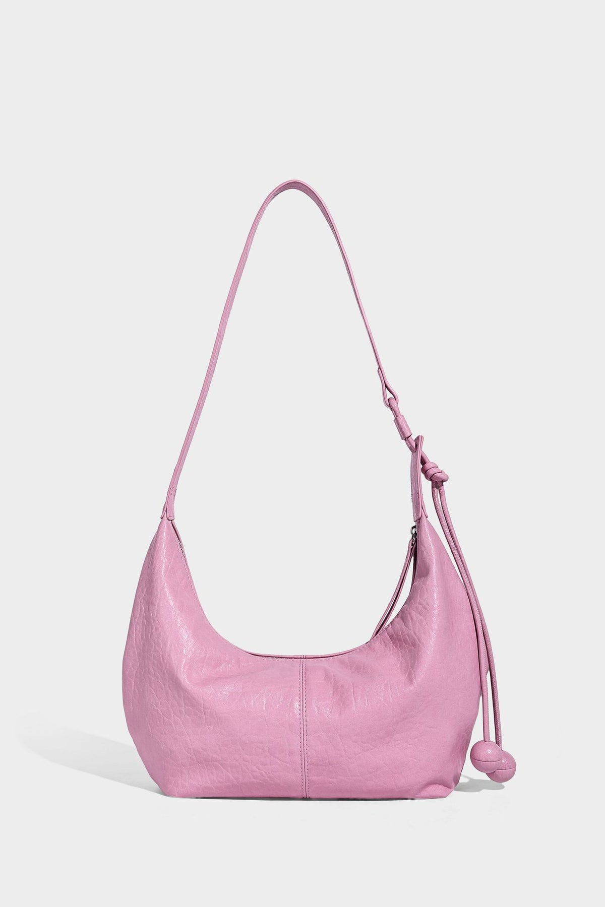 Slouchy crescent half-moon shoulder bag in pink pebbled textured finish with floral charm and knotted side detail, detail