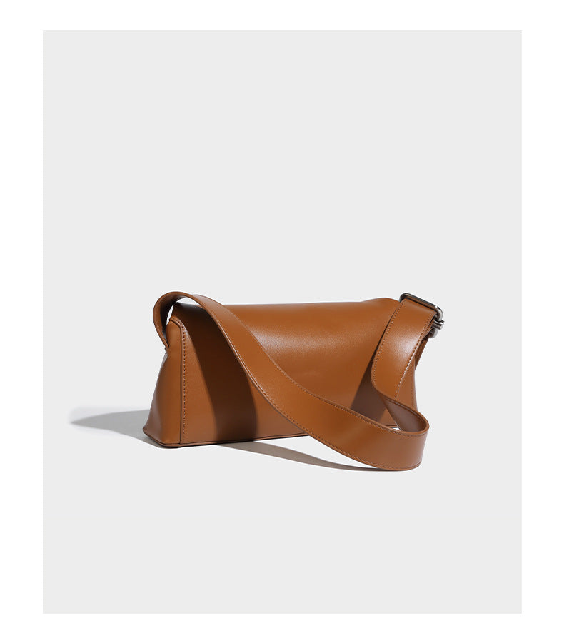Compact structured baguette shoulder bag with smooth leather-look finish, zip top, and adjustable silver-buckle strap, detail