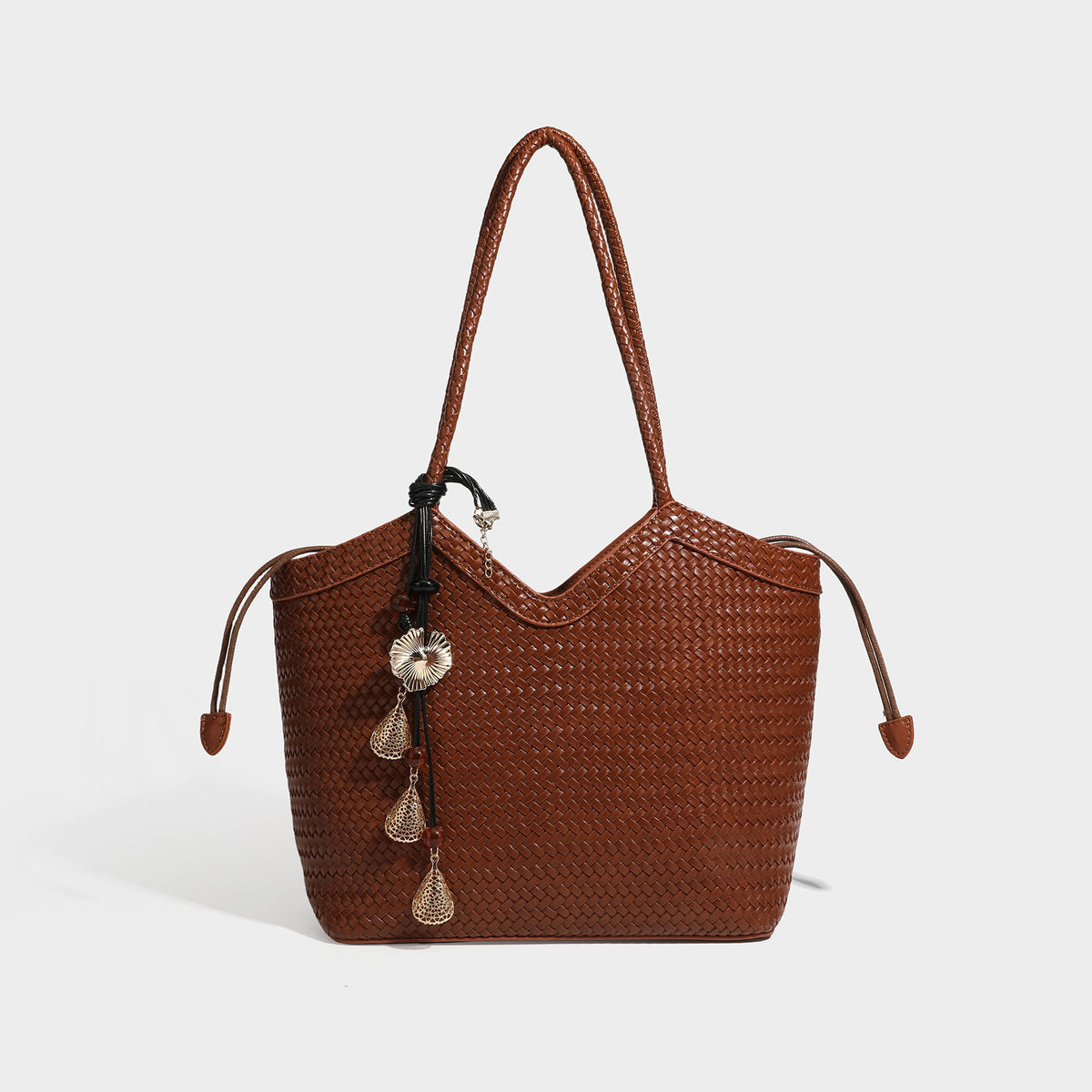Olivgrüne Tote-Bag in Korbgeflecht-Optik mit dunkelbraunen geflochtenen Schulterriemen, seitlichen Zugbändern und Perlenanhänger in Goldoptik