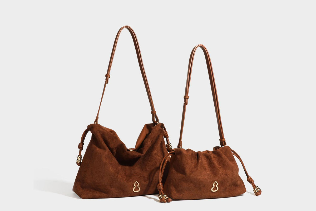 Suede-look drawstring shoulder bag in brown with smooth trim, knotted bead drawstring closure, slim adjustable strap, and