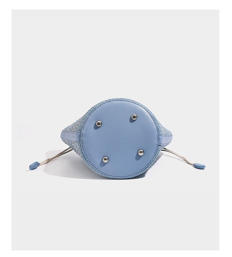 Light blue open-weave woven bucket tote bag with long braided shoulder straps, drawstring side ties, and attached mini pouch