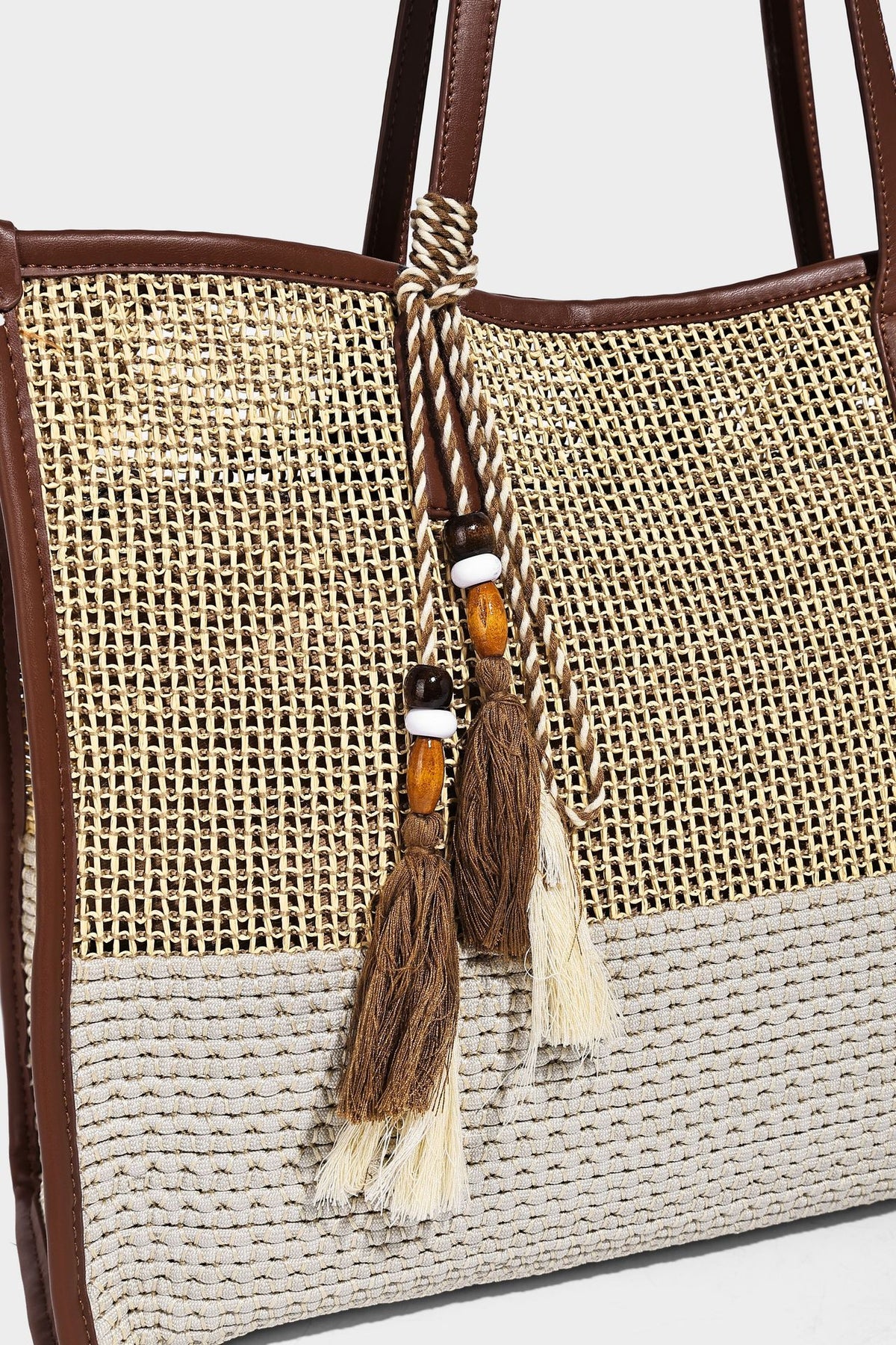 Große Tote-Bag aus grob geflochtenem Stroh in Beige und Creme mit dunkelbraunen Details in Lederoptik, langen Schulterriemen und einem mit Perlen verzierten