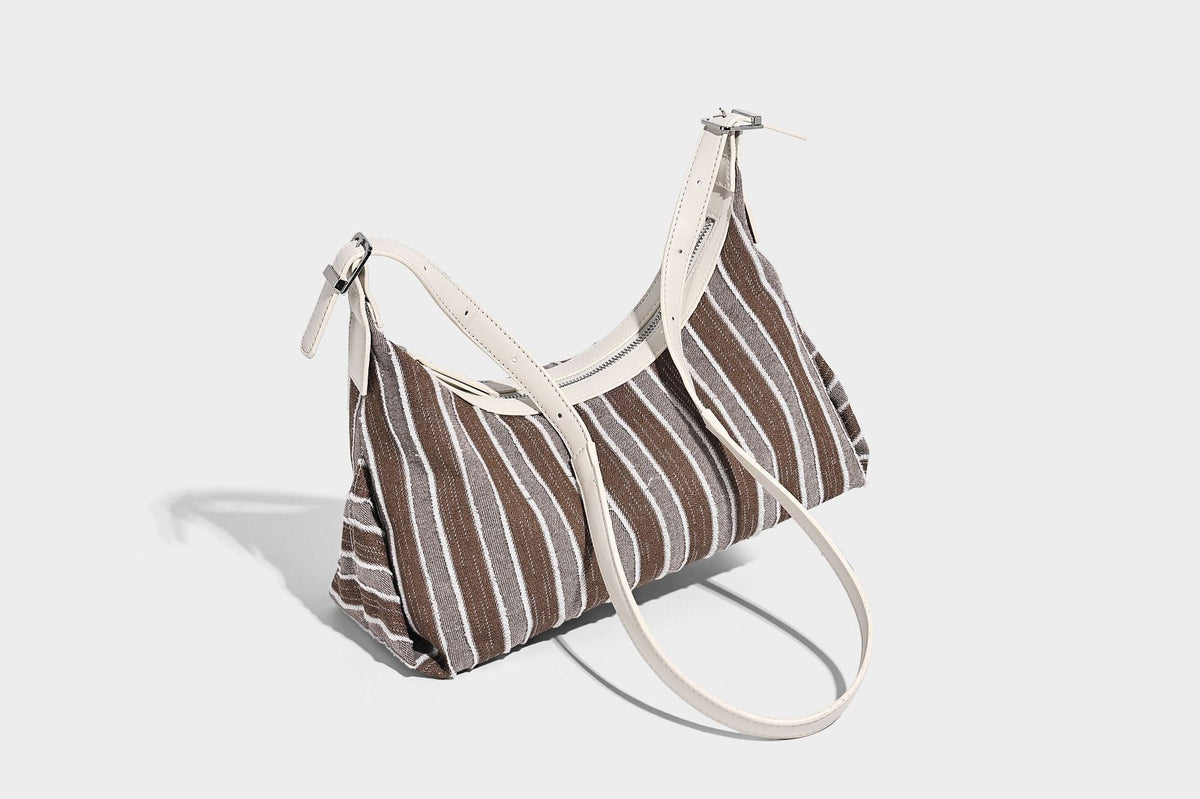 Weich fallende Hobo-Tasche aus gestreiftem Webmaterial mit kontrastierendem Besatz in Creme, Reißverschluss oben und verstellbarem Riemen mit Schnalle in Silberoptik, Detailaufnahme