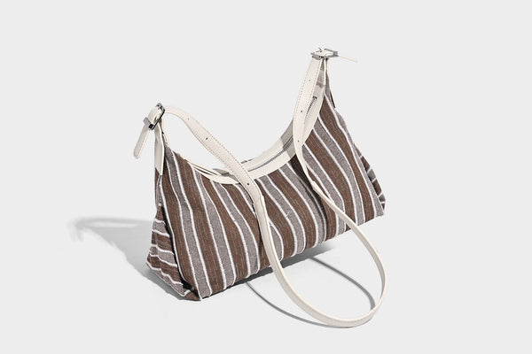 Weich fallende Hobo-Tasche aus gestreiftem Webmaterial mit kontrastierendem Besatz in Creme, Reißverschluss oben und verstellbarem Riemen mit Schnalle in Silberoptik, Detailaufnahme