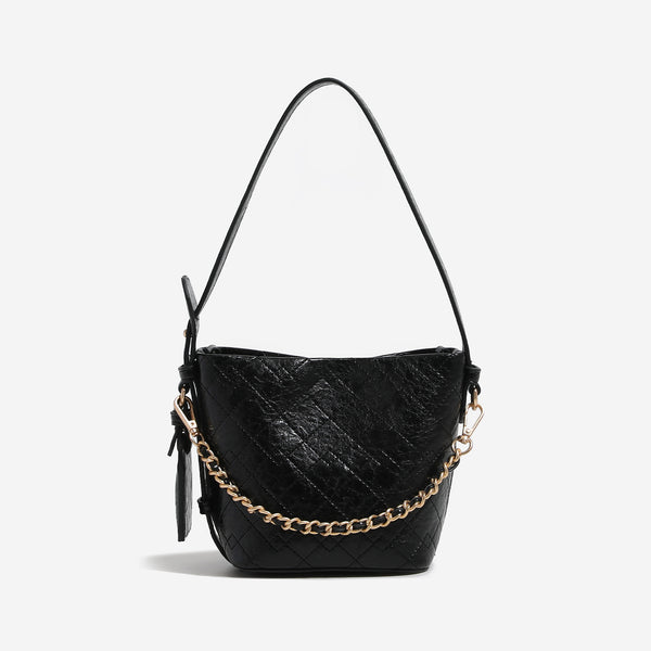 Small diamond-quilted bucket bag with gold-tone chain accent, heart strap detail, hanging tag, and matching zip coin pouch
