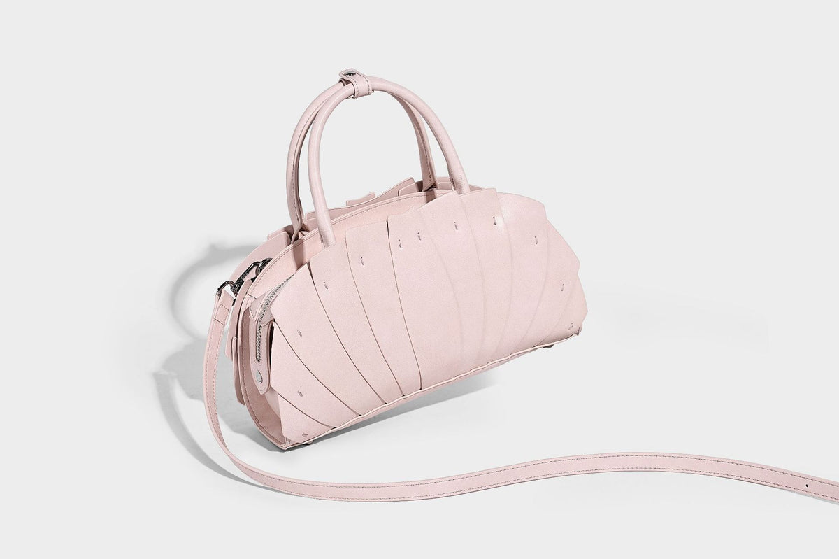 Structured dome satchel with fan-pleated leather-look exterior, dual top handles, and detachable shoulder strap, detail view