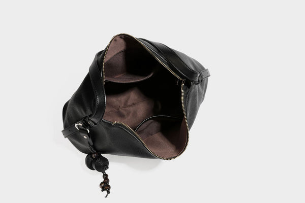 Slouchy hobo shoulder bag with pebbled leather-look finish, zip-top closure, gold-tone hardware, and hanging bead charm