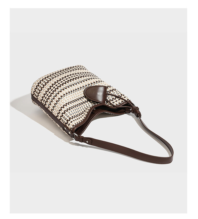 Woven stripe bucket shoulder bag in cream and dark brown with leather-look trim, knotted adjustable strap, and small shield